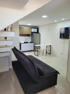 een woonkamer met een zwarte bank en een keuken bij Excelente Casa Duplex em Tramandaí in Tramandaí