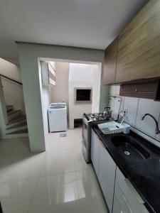 a kitchen with a stove and a sink in it at Excelente Casa Duplex em Tramandaí in Tramandaí