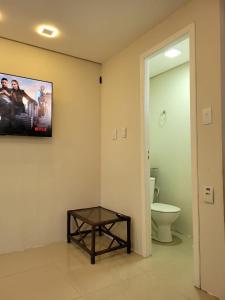 a bathroom with a toilet and a tv on the wall at Excelente Casa Duplex em Tramandaí in Tramandaí
