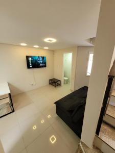 uma sala de estar com um sofá preto e uma televisão de ecrã plano em Excelente Casa Duplex em Tramandaí em Tramandaí