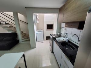 a kitchen with a sink and a refrigerator in it at Excelente Casa Duplex em Tramandaí in Tramandaí