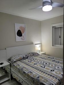 een slaapkamer met een bed met een dekbed erop bij Excelente Casa Duplex em Tramandaí in Tramandaí