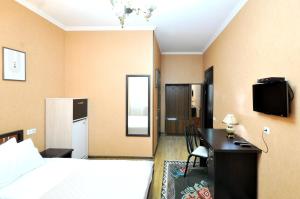 a bedroom with a bed and a desk and a television at Flamingo Hotel in Tbilisi City