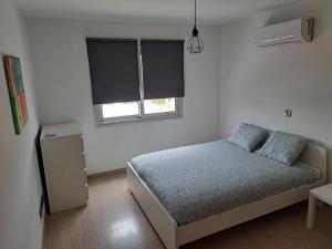 a white bedroom with a bed and a window at Modern Suite, XL balcony, parking in Nicosia