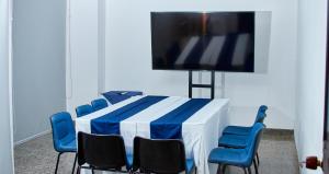 Habitación con mesa con sillas azules y TV de pantalla plana. en Hotel Ruittoque D Prada, en Bucaramanga