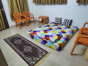 a bedroom with a colorful bed and chairs and a rug at Khushi Villa in Kakarmatha