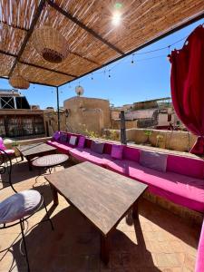 une terrasse avec un canapé rose, des tables et des chaises dans l'établissement Dar Attajalli, à Fès