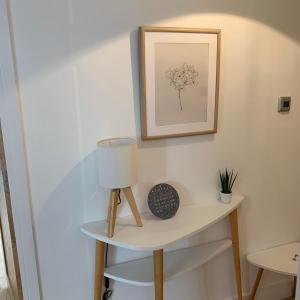 a table with a lamp and a picture on the wall at Woodview Cottage in Glamis