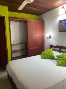 1 dormitorio con 1 cama blanca grande con almohadas verdes en Hotel Nueva Granada en Santa Marta