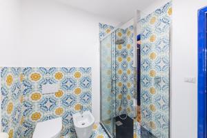 a bathroom with a toilet and blue and white tiles at Castalia Apartments & Rooms Duomo Taormina in Taormina +100 photos