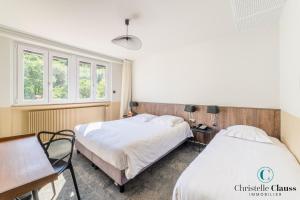 a bedroom with two beds and a desk and windows at Hotel Restaurant au Floridor in Thann