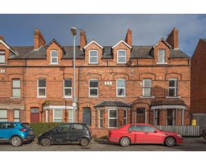 three cars parked in front of a large brick building at Central Belfast Apartments Eden in Belfast