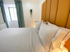 a bedroom with a bed with white sheets and a window at Vibrant Setúbal II in Setúbal +17 photos