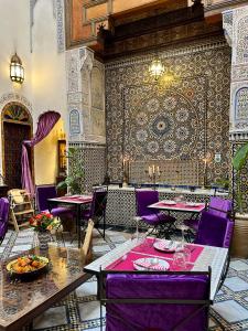 een restaurant met paarse tafels en paarse stoelen bij Dar Attajalli in Fès