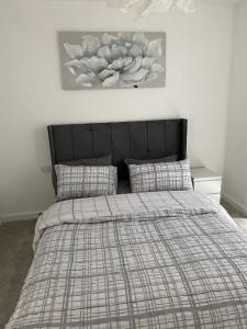 a bed with a plaid comforter and pillows in a bedroom at Escape Homes in Barking