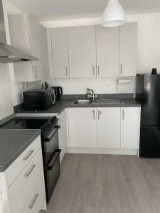a kitchen with white cabinets and a black refrigerator at Escape Homes in Barking