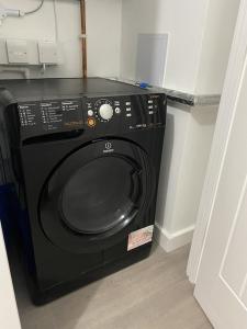 a black washing machine in a corner of a room at Escape Homes in Barking