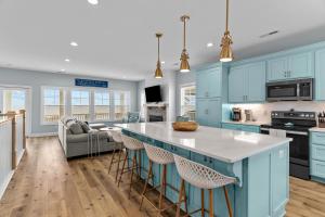 a kitchen with blue cabinets and a island with bar stools at Heaven's Outpost in Holden Beach