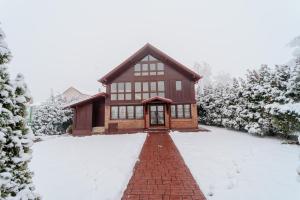 una casa cubierta de nieve con un camino de ladrillo rojo en Vila LALUKO en Zlatibor