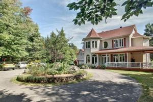 a large house with a car parked in the driveway at Majestic Retreat in the Laurentians in Morin Heights