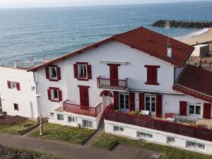 a white house with red windows and the ocean at T3 VUE MER A 20 mètres de la PLAGE ANGLET BIARRITZ in Anglet