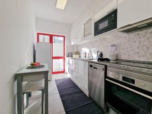 una cucina con elettrodomestici bianchi e una porta rossa di Apartment Praia Rocha Candimar Confort a Portimão