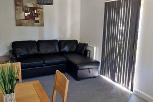 un sofá de cuero negro en una sala de estar con mesa en Greenhithe Cosy Apartment, Netflix and Sport Channels, en Kent