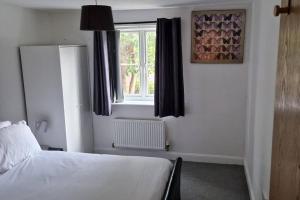 a bedroom with a white bed and a window at Greenhithe Cosy Apartment, Netflix and Sport Channels in Kent