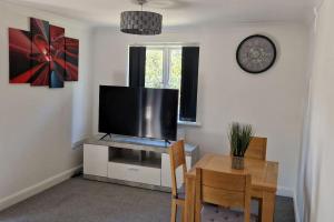 Greenhithe Cosy Apartment, Netflix and Sport Channels في Kent: غرفة معيشة مع طاولة وتلفزيون وطاولة وكراسي