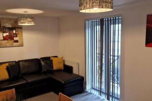 a living room with a black leather couch and a window at Greenhithe Cosy Apartment, Netflix and Sport Channels in Kent