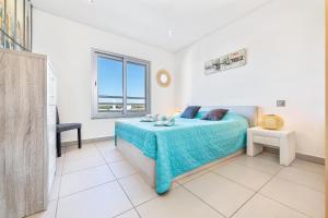 a bedroom with a bed with a blue blanket and a window at Apartamento Michel Sea View Algarve in Albufeira