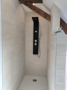 a shower in a bathroom with a phone on the wall at Chambre d'hôtes in Beaumont-Pied-de-Boeuf