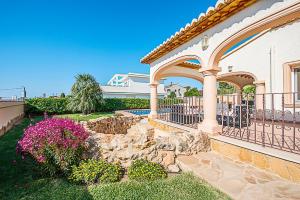 una casa con una valla y un jardín de rocas en Villa Almendros - PlusHolidays, en Calpe