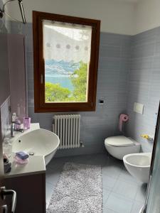 łazienka z umywalką, toaletą i oknem w obiekcie Lilli - Casa sul Lago w mieście Dervio
