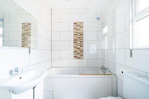 Baño blanco con bañera y lavamanos en (Kensington-Olympia-Museums ) Apartment Central London, en Londres