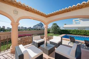 a patio with white furniture and a swimming pool at Villa Almendros - PlusHolidays in Calpe