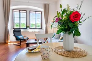wazon z czerwoną różą na stole w obiekcie Starý farhof w mieście Kutná Hora