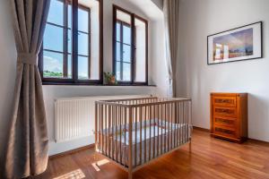 a baby crib in a room with two windows at Starý farhof in Kutná Hora
