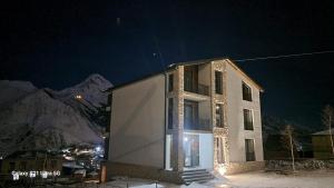 a white building with a balcony on it at night at Kazbegi 4U in Stepantsminda
