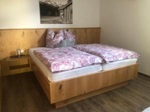 a bedroom with a wooden bed with a purple comforter at Haus Schmid in Tobadill