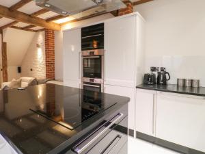 La cuisine est équipée de placards blancs et d'un four avec plaques de cuisson. dans l'établissement The Old Dairy House, à Ashbourne