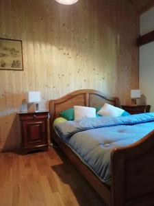 a bedroom with a bed with a wooden headboard and a table at La Grange in Le Noyer