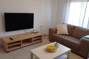 a living room with a couch and a flat screen tv at One bedroom private apartment - quiet near a park in Beer Sheva