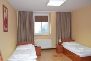 Cette chambre comprend 2 lits et une fenêtre. dans l'établissement Hotel i Restauracja Jaskolka, à Alojzów