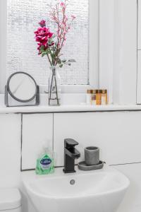 ein Waschbecken mit einer Vase mit einer Blume darauf in der Unterkunft 4 bedroom House Free Parking Contractor's Haven in Chelmsford