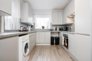 a kitchen with white cabinets and a washer and dryer at 4 bedroom House Free Parking Contractor's Haven in Chelmsford