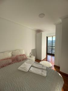 a white bedroom with a large bed with a window at Moment Collector in Ourense