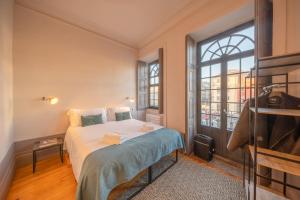 een slaapkamer met een bed en een groot raam bij Feel Porto Antique Poveiros Flats in Porto