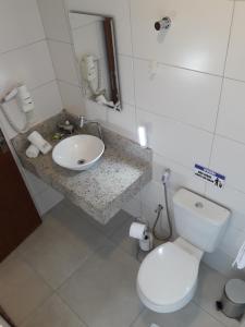 a bathroom with a white toilet and a sink at Suítes Cambucá in Ilhabela