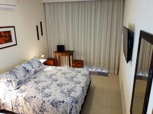1 dormitorio con 1 cama y TV en Suítes Cambucá en Ilhabela